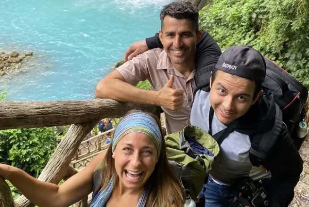 Three people standing on a bridge next to the Rio Celeste Waterfall Hike on a waterfall hike.