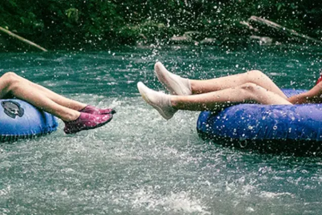 Two people riding tubes down in Rio Celeste