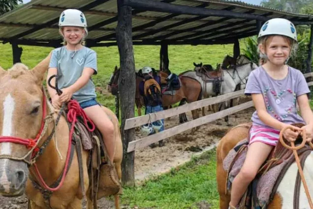 Two children enjoying Rio Celeste Horseback Riding on a farm.