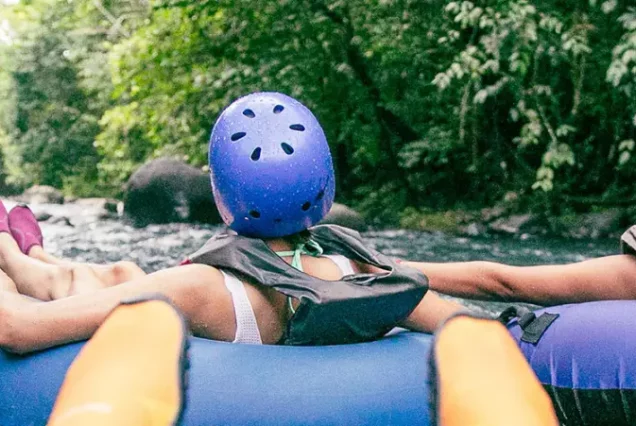 Two people riding down Rio Celeste on inflatable tubes.