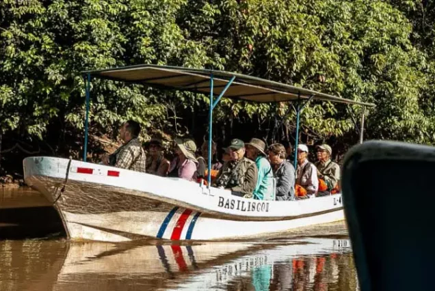 A group of people riding in a boat down a river, admiring the Caño Negro Wildlife Refuge.