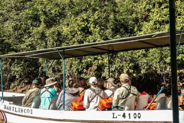 A group of people riding in a boat through the Caño Negro Wildlife Refuge on a river.