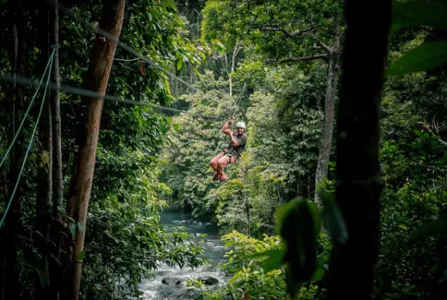 A person Rio Celeste zip-lining through the Rio Celeste jungle.