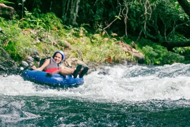 A woman riding an inflatable tube down a river.