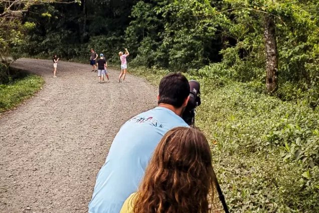 A man and a child are enjoying the Responsible and Sustainable Sloth Tour on a dirt road while snapping pictures.