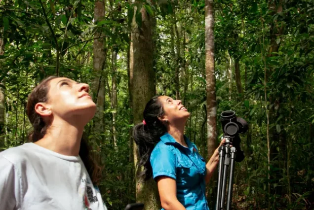 Two women standing in a Responsible and Sustainable Sloth Tour with a camera in their hands.