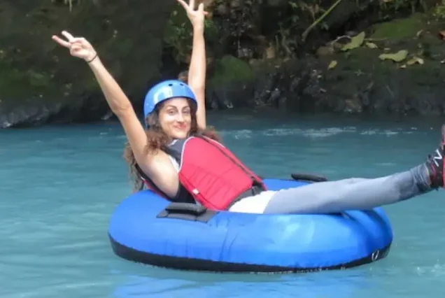 A woman floats down a river on an inflatable tube in Rio Celeste