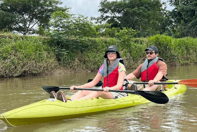 Two people paddling down a river in a kayak.