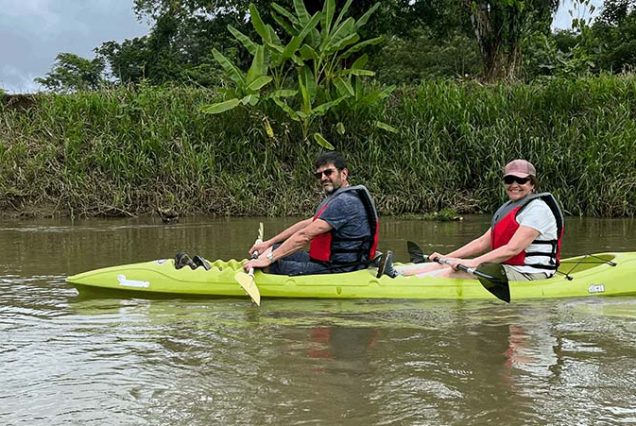 Two people paddling in a kayak on a river.