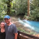 A couple posing for photo, at the background The Rio Celeste