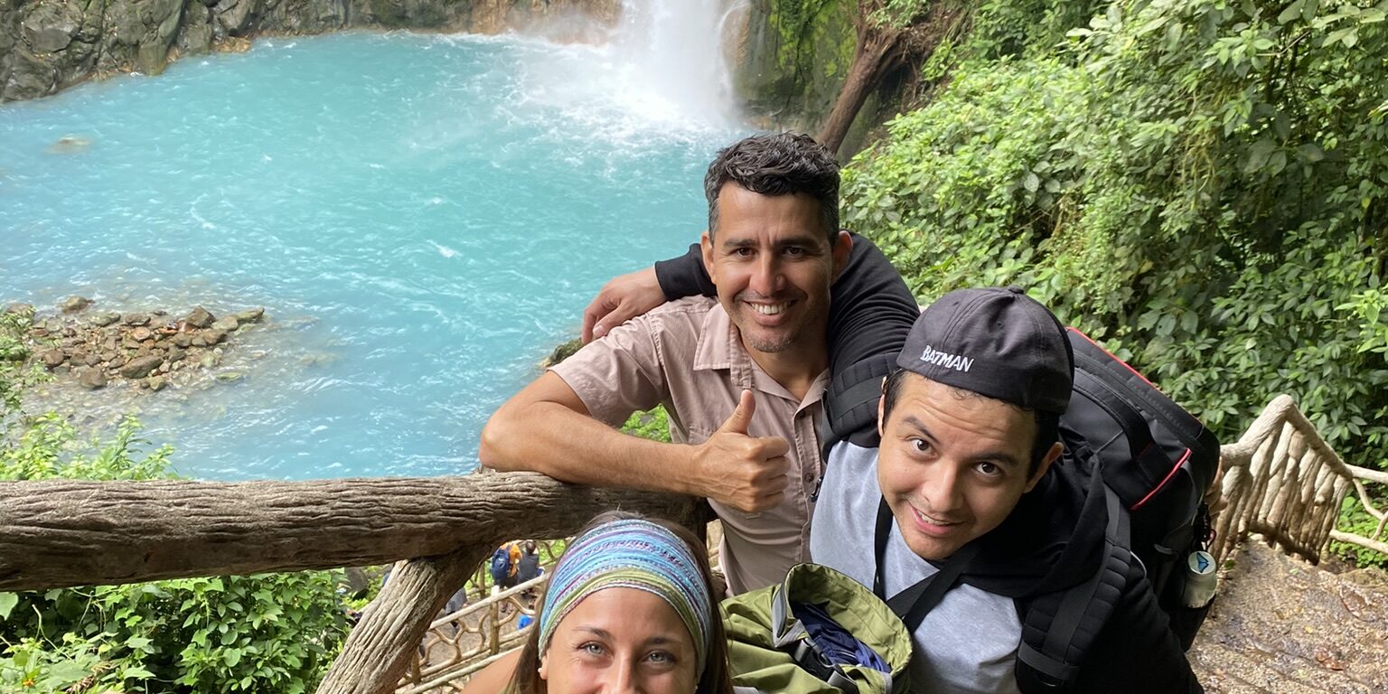 A group of friends having behind the Rio Celeste Waterfall
