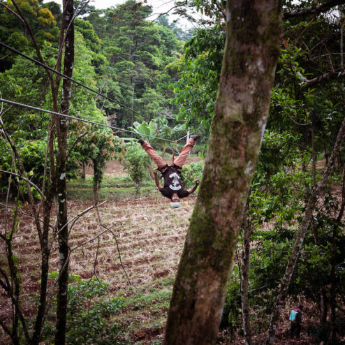 A man in the middle of the zip line upside down