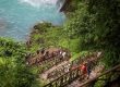 A group of people are walking up stairs to a waterfall in the Rio Celeste location.