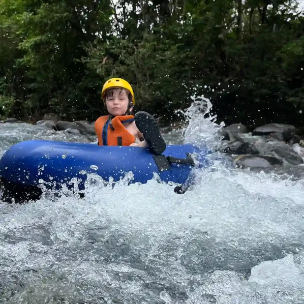 Young individual tubing alone in Rio Celeste with splashing water around.