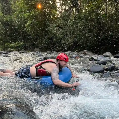 Man tubing in Rio Celeste on a rocky stream.