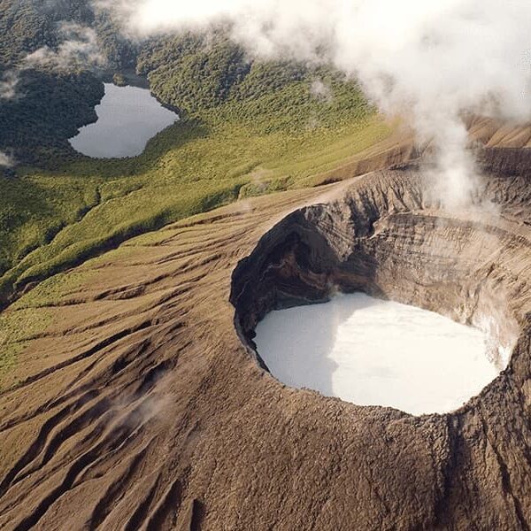 Aerial view of a volcanic crater with a white lake at its center, surrounded by lush rainforests and two smaller lakes. White clouds hover above the landscape, capturing the natural beauty typical of Costa Rica Travel.