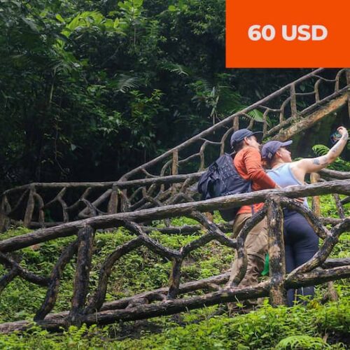 Two people stand on a wooden forest staircase, taking a selfie. Text in the corner reads “60 USD.” Two people stand on a wooden forest staircase, taking a selfie. Text in the corner reads “60 USD.”