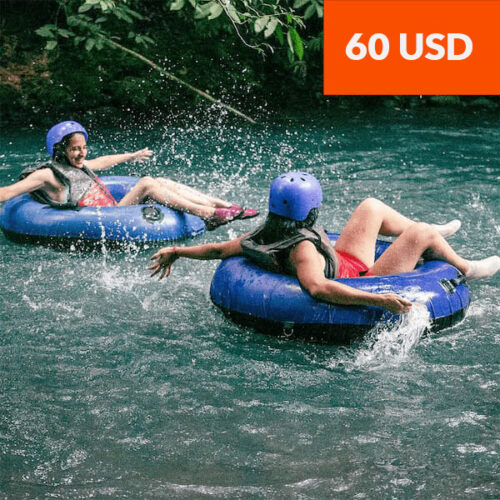 Two people in blue helmets and life vests tubing down a river on a Rio Celeste hiking excursion. Text overlay reads “60 USD”. Two people in blue helmets and life vests tubing down a river on a Rio Celeste hiking excursion. Text overlay reads “60 USD”.